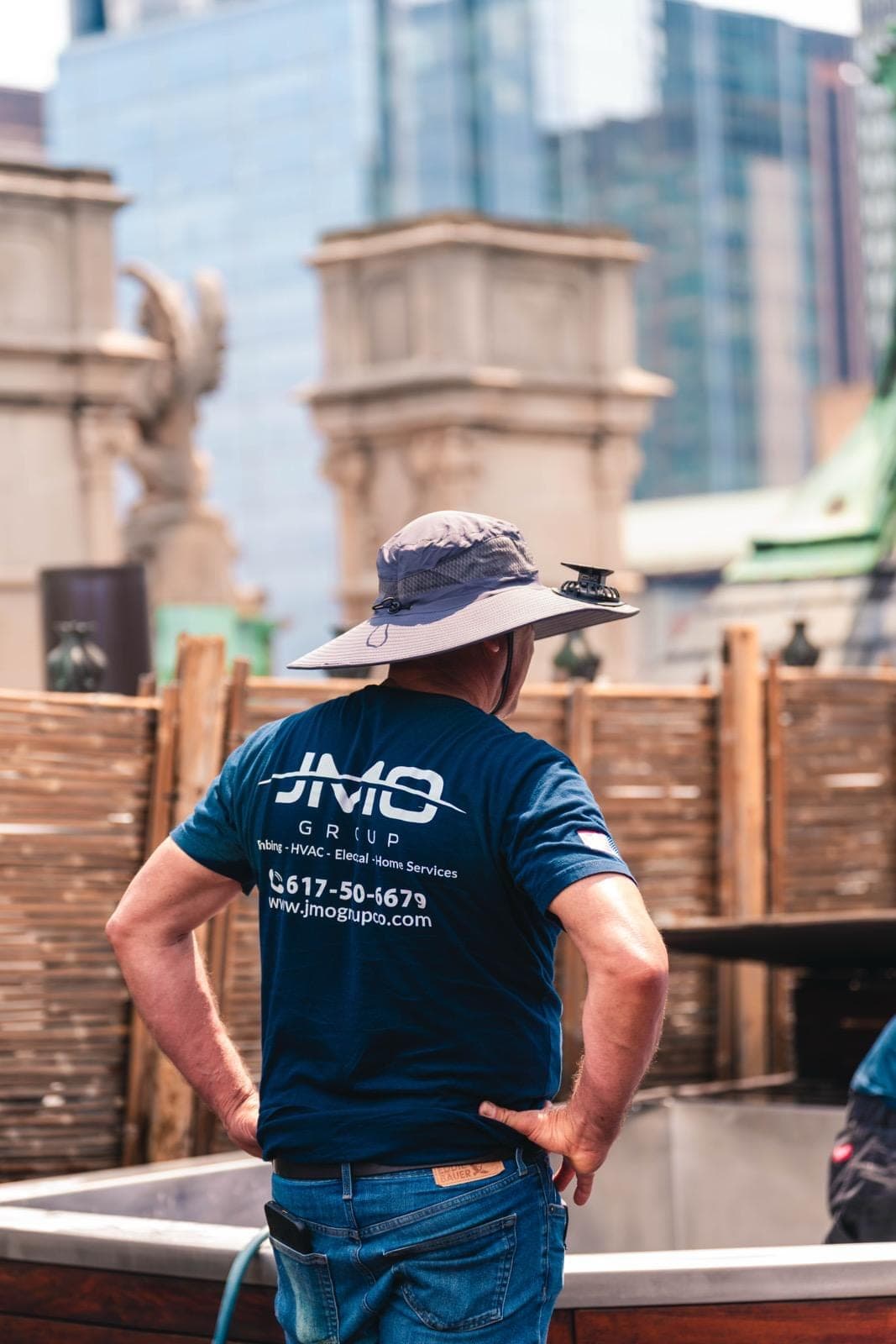 JMO technician on a rooftop with the Boston skyline behind