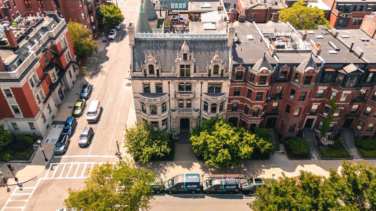 Aerial view of a Boston property and surrounding buildings, with JMO service vans parked outside