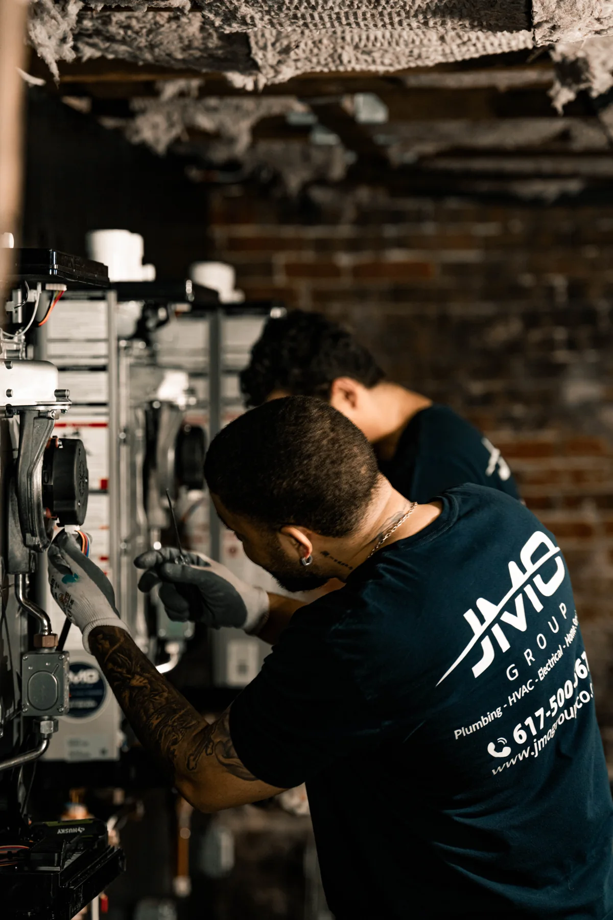 Technician working inside an open wall-mounted mechanical unit