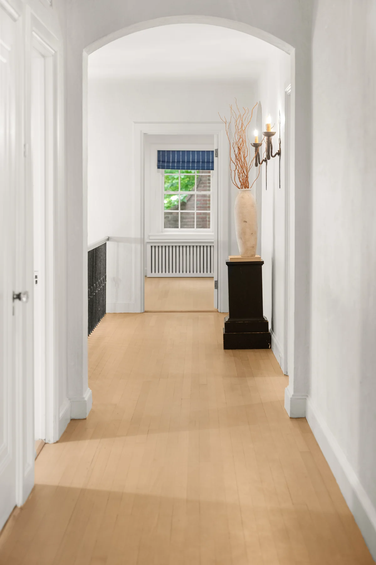 Arched hallway with white door casings, wall trim, and wood flooring at 372 Warren Street