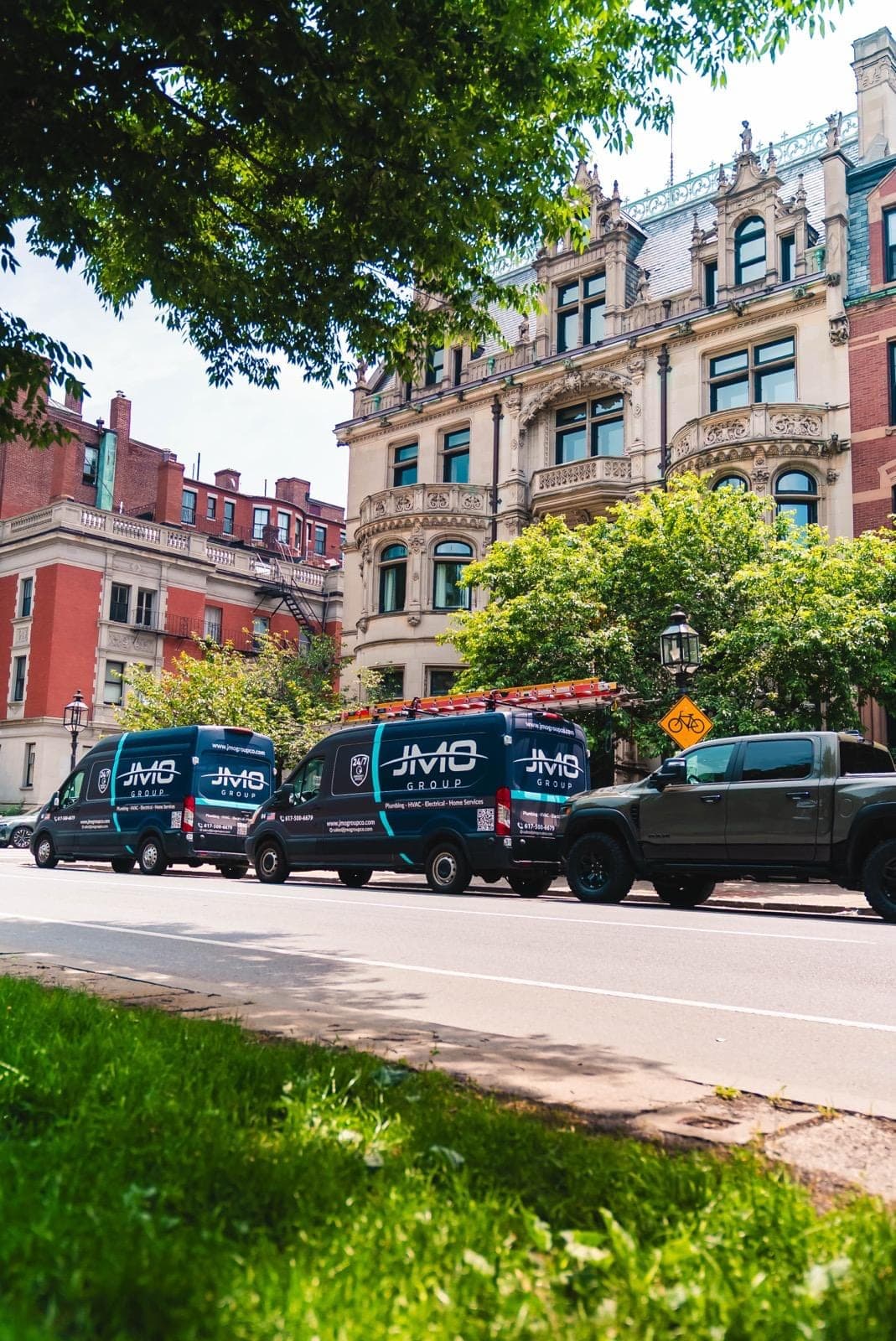 JMO service vans and a pickup parked outside a historic Boston property