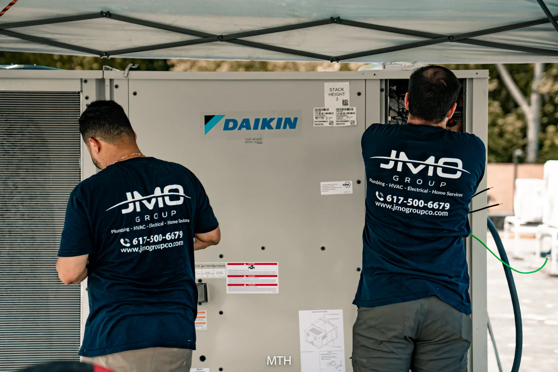 Two JMO technicians working together on an outdoor HVAC unit