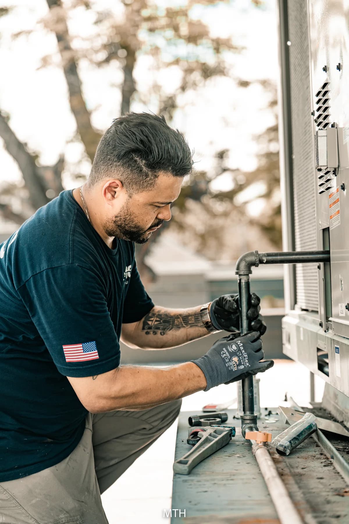JMO technician working on pipework beside an outdoor HVAC unit