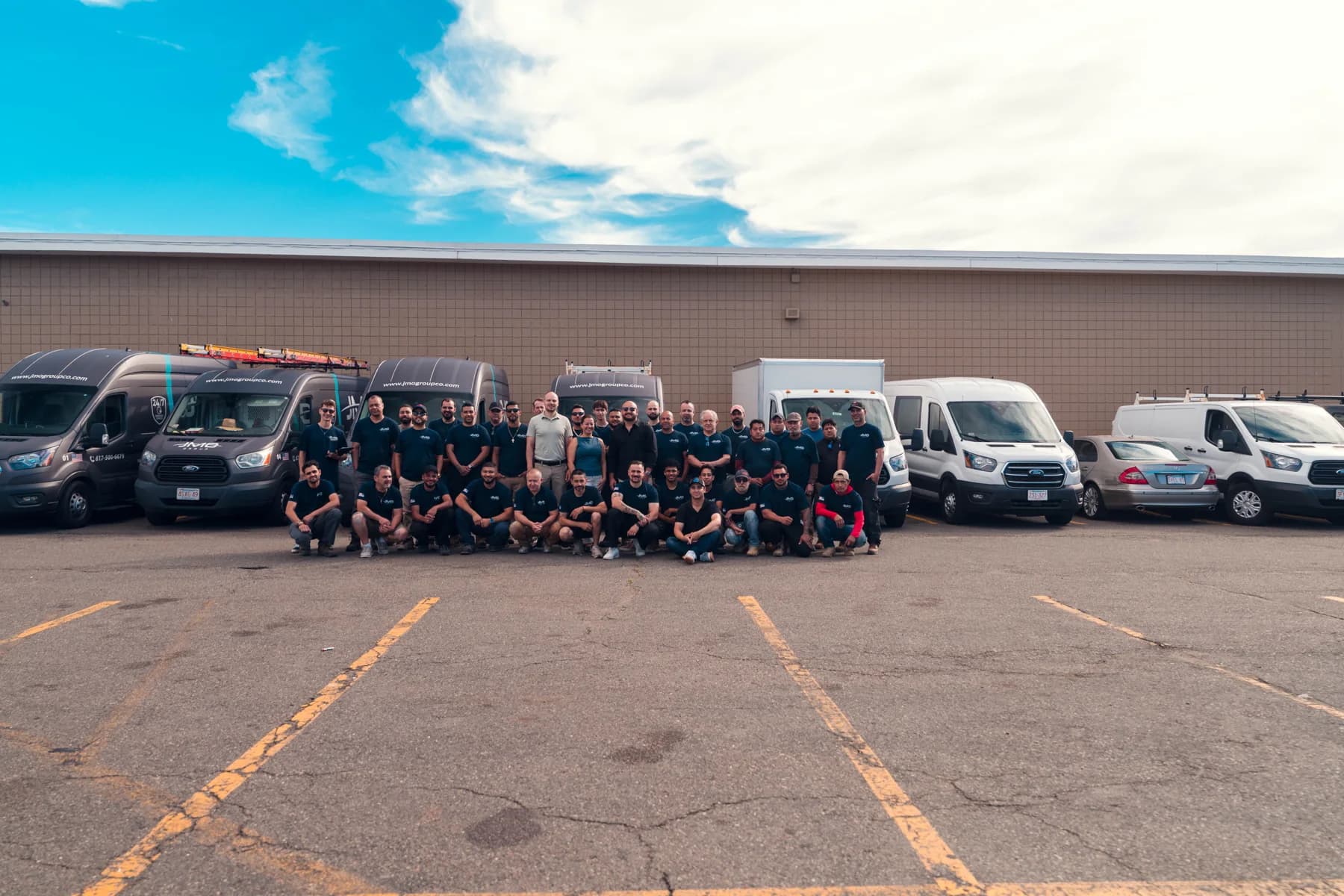 The JMO team standing together in front of branded service vans